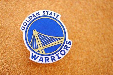 KYIV, UKRAINE - 23 Şubat 2025 Golden State Warriors basketbol takımı rozeti altın sarısı parıltılı arka plan pankartıyla uzanır