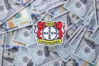 KYIV, UKRAINE - 23 Şubat 2025 Bayer 04 Leverkusen futbol kulübü rozeti yüzlük banknotların üzerinde yatıyor