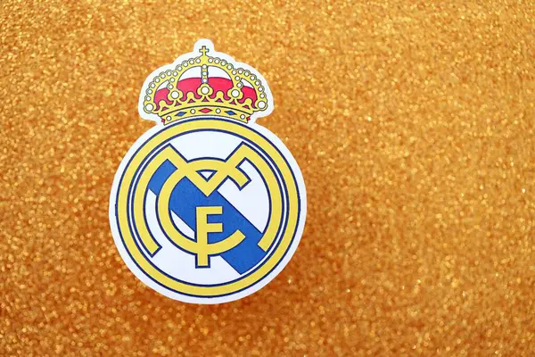 KYIV, UKRAINE - 23 Şubat 2025 Real Madrid CF futbol kulübü rozeti altın sarısı parıltılı arka plan pankartıyla uzanır