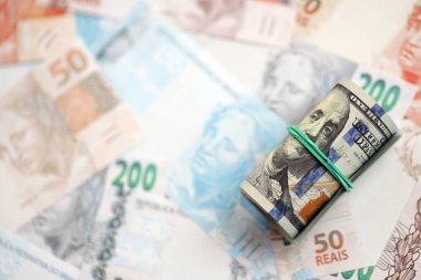 Bir tomar Amerikan doları büyük miktarda Brezilya banknotlarının üzerinde yatıyor. Amerikan parası Brezilya 'nın para akışında yatıyor. Brezilya 'da ekonomi ve döviz kuru kavramı