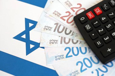Israel New Shekels banknotları ve hesap makinesi bayrağın üzerinde. İsrail 'in mevcut para faturaları ve kalibreleri büyük oranda bayrakta yatıyor. İsrail 'de vergilendirme ve para kavramı