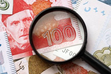 Pakistan banknotları ve büyüteç. Pakistan 'ın mevcut para ve büyüteç faturaları büyük miktarda masanın üzerinde duruyor. Pakistan 'da mali izleme ve vergilendirme kavramı