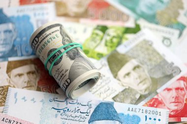 Amerikan dolarlarının rulosu Pakistan 'daki büyük miktardaki banknotların üzerinde yatıyor. Amerikan para demeti Pakistan 'ın para banknotlarında yatıyor. Pakistan 'da ekonomi ve döviz kuru kavramı