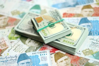 Amerikan dolarları yığını Pakistan Rupi banknotlarının büyük bir miktarına yakın duruyor. Amerikan para demeti Pakistan 'ın para banknotlarında yatıyor. Pakistan 'da ekonomi ve döviz kuru kavramı