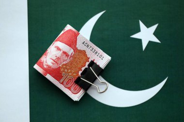Pakistan bayrağı üzerinde Pakistan banknotları. Pakistan 'ın mevcut para faturaları büyük miktarlarda pankartta yatıyor. Pakistan 'da ekonomi ve ticaret kavramı