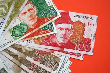 Pakistan kırmızı arka planda banknotlar halinde. Pakistan 'ın mevcut para faturaları büyük miktarda masada yatıyor. Pakistan 'da iş ve yatırım kavramı