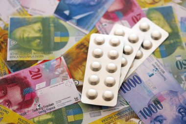 İsviçre frangı ve ilaç hapları. Mevcut para ve uyuşturucu banknotları büyük miktarda masada yatıyor. İsviçre 'de ilaç ve eczane kavramı