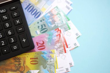 İsviçre frangı banknotları ve hesap makinesi maviye. Mevcut frank para faturaları ve calc büyük miktarda masada yatıyor. İsviçre 'de vergilendirme ve para konsepti