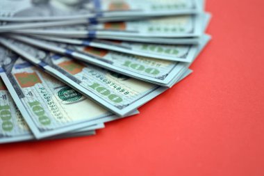 Kırmızı arka planda büyük miktarda yüz dolarlık banknot var. ABD 'de vergilendirme ve para yapma kavramı