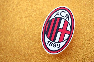 KYIV, UKRAINE - 23 Şubat 2025 AC Milan futbol kulübü rozeti altın sarısı parıltılı arka plan pankartıyla uzanır