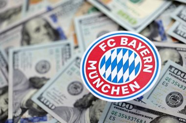 KYIV, UKRAINE - 23 Şubat 2025 Bayern Münih futbol kulübü rozeti 100 dolarlık banknotların üzerinde yatıyor