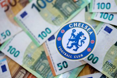 KYIV, UKRAINE - 23 Şubat 2025 Chelsea FC futbol kulübü rozeti büyük miktarda EURO para banknotlarının üzerinde yatıyor