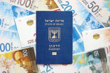 Israel New Shekels banknotları ve pasaportu. İsrail 'in mevcut para faturaları ve biyometrik geçiş kartı büyük miktarda masada yatıyor. İsrail 'de seyahat ve tatil kavramı