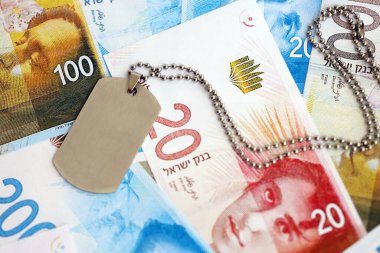 İsrail Yeni Şekelleri 'nin banknotları ve askeri simgesi. İsrail 'in mevcut para faturaları ve künyeleri büyük miktarda masada yatıyor. İsrail 'de askerlik kavramı