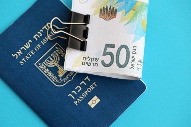 Israel New Shekels banknotları ve mavi arka planda pasaport. İsrail 'in şu anki para banknotları büyük oranda mavi üzerine yatar. İsrail 'de finans ve nakit kavramı