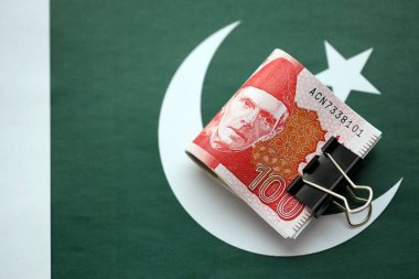 Pakistan bayrağı üzerinde Pakistan banknotları. Pakistan 'ın mevcut para faturaları büyük miktarlarda pankartta yatıyor. Pakistan 'da ekonomi ve ticaret kavramı