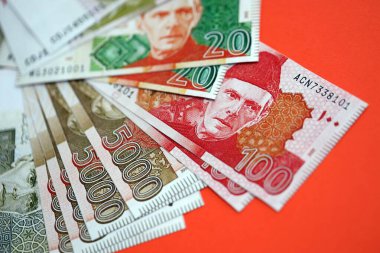 Pakistan kırmızı arka planda banknotlar halinde. Pakistan 'ın mevcut para faturaları büyük miktarda masada yatıyor. Pakistan 'da iş ve yatırım kavramı