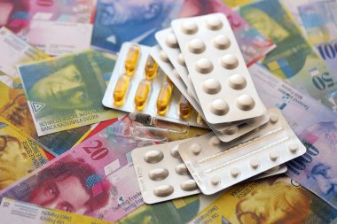 İsviçre frangı ve ilaç hapları. Mevcut para ve uyuşturucu banknotları büyük miktarda masada yatıyor. İsviçre 'de ilaç ve eczane kavramı
