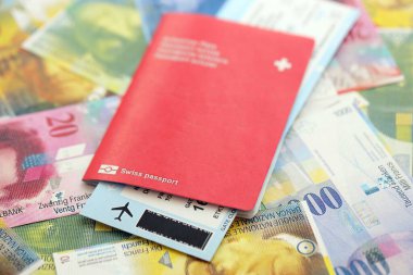 İsviçre frangı banknotları ve biletli pasaport. Mevcut banknotlar ve biyometrik geçiş kartları büyük miktarda masada yatıyor. İsviçre 'de seyahat ve tatil kavramı