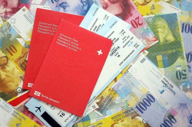 İsviçre frangı banknotları ve biletli pasaport. Mevcut banknotlar ve biyometrik geçiş kartları büyük miktarda masada yatıyor. İsviçre 'de seyahat ve tatil kavramı
