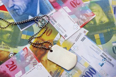 İsviçre frangı banknotları ve askeri jeton. Mevcut banknotlar ve künyeler masanın üzerinde büyük miktarda duruyor. İsviçre 'de askerlik konsepti