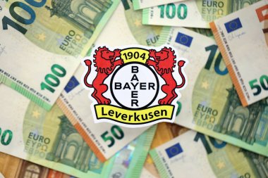 KYIV, UKRAINE - 23 Şubat 2025 Bayer 04 Leverkusen futbol kulübü rozeti büyük miktarda EURO para banknotları üzerinde yatıyor
