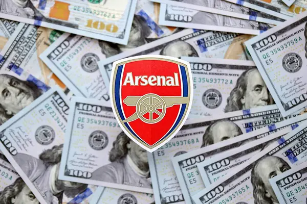 KYIV, UKRAINE - 23 Şubat 2025 Arsenal FC futbol kulübü rozeti yüzlük banknotların üzerinde yatıyor