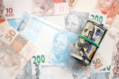 Bir tomar Amerikan doları büyük miktarda Brezilya banknotlarının üzerinde yatıyor. Amerikan parası Brezilya 'nın para akışında yatıyor. Brezilya 'da ekonomi ve döviz kuru kavramı