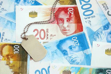 İsrail Yeni Şekelleri 'nin banknotları ve askeri simgesi. İsrail 'in mevcut para faturaları ve künyeleri büyük miktarda masada yatıyor. İsrail 'de askerlik kavramı