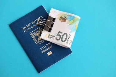 Israel New Shekels banknotları ve mavi arka planda pasaport. İsrail 'in şu anki para banknotları büyük oranda mavi üzerine yatar. İsrail 'de finans ve nakit kavramı