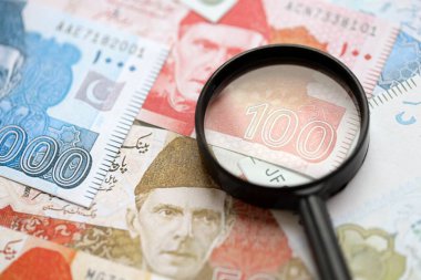 Pakistan banknotları ve büyüteç. Pakistan 'ın mevcut para ve büyüteç faturaları büyük miktarda masanın üzerinde duruyor. Pakistan 'da mali izleme ve vergilendirme kavramı