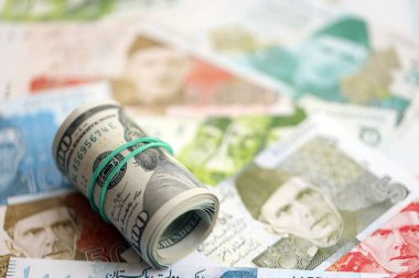 Amerikan dolarlarının rulosu Pakistan 'daki büyük miktardaki banknotların üzerinde yatıyor. Amerikan para demeti Pakistan 'ın para banknotlarında yatıyor. Pakistan 'da ekonomi ve döviz kuru kavramı