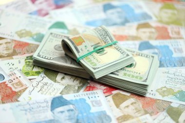 Amerikan dolarları yığını Pakistan Rupi banknotlarının büyük bir miktarına yakın duruyor. Amerikan para demeti Pakistan 'ın para banknotlarında yatıyor. Pakistan 'da ekonomi ve döviz kuru kavramı