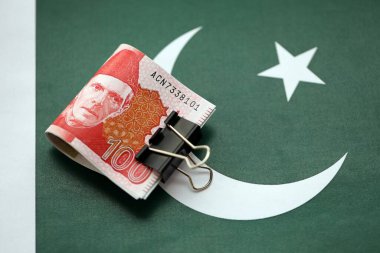 Pakistan bayrağı üzerinde Pakistan banknotları. Pakistan 'ın mevcut para faturaları büyük miktarlarda pankartta yatıyor. Pakistan 'da ekonomi ve ticaret kavramı