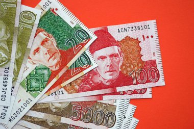 Pakistan kırmızı arka planda banknotlar halinde. Pakistan 'ın mevcut para faturaları büyük miktarda masada yatıyor. Pakistan 'da iş ve yatırım kavramı