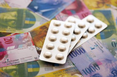 İsviçre frangı ve ilaç hapları. Mevcut para ve uyuşturucu banknotları büyük miktarda masada yatıyor. İsviçre 'de ilaç ve eczane kavramı