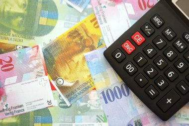 İsviçre frangı banknotları ve hesap makinesi. Mevcut frank para faturaları ve calc büyük miktarda masada yatıyor. İsviçre 'de vergilendirme ve para konsepti