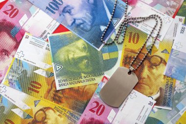 İsviçre frangı banknotları ve askeri jeton. Mevcut banknotlar ve künyeler masanın üzerinde büyük miktarda duruyor. İsviçre 'de askerlik konsepti