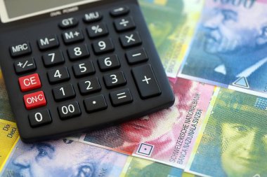İsviçre frangı banknotları ve hesap makinesi. Faturalar ve kalibreler masanın üzerinde duruyor. İsviçre 'de vergilendirme ve para konsepti