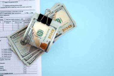 Birleşik Devletler 'in 100 dolarlık banknotları bireysel gelir vergisi iadesi formlarıyla dolu. ABD 'de vergilendirme ve muhasebe kavramı