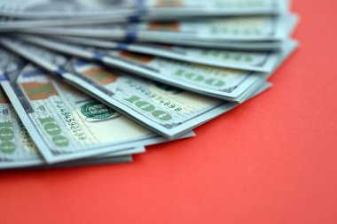 Kırmızı arka planda büyük miktarda yüz dolarlık banknot var. ABD 'de vergilendirme ve para yapma kavramı