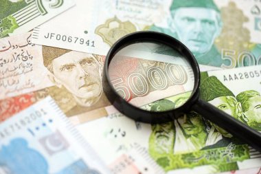 Pakistan banknotları ve büyüteç. Pakistan 'ın mevcut para ve büyüteç faturaları büyük miktarda masanın üzerinde duruyor. Pakistan 'da mali izleme ve vergilendirme kavramı