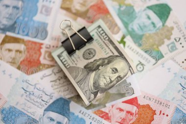 Amerikan dolarlarının rulosu Pakistan 'daki büyük miktardaki banknotların üzerinde yatıyor. Amerikan para demeti Pakistan 'ın para banknotlarında yatıyor. Pakistan 'da ekonomi ve döviz kuru kavramı