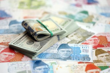Amerikan dolarları yığını Pakistan Rupi banknotlarının büyük bir miktarına yakın duruyor. Amerikan para demeti Pakistan 'ın para banknotlarında yatıyor. Pakistan 'da ekonomi ve döviz kuru kavramı