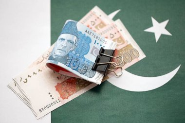 Pakistan bayrağı üzerinde Pakistan banknotları. Pakistan 'ın mevcut para faturaları büyük miktarlarda pankartta yatıyor. Pakistan 'da ekonomi ve ticaret kavramı