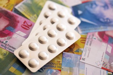 İsviçre frangı ve ilaç hapları. Mevcut para ve uyuşturucu banknotları büyük miktarda masada yatıyor. İsviçre 'de ilaç ve eczane kavramı