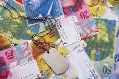 İsviçre frangı banknotları ve askeri jeton. Mevcut banknotlar ve künyeler masanın üzerinde büyük miktarda duruyor. İsviçre 'de askerlik konsepti