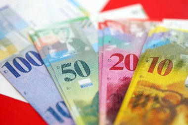 İsviçre frangı banknotları ve bayrağı. Mevcut para banknotları büyük miktarda bayrağın üzerinde yatıyor. İsviçre 'de iş ve yatırım kavramı