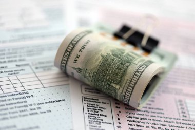 Birleşik Devletler 'in 100 dolarlık banknotları bireysel gelir vergisi iadesi formlarıyla dolu. ABD 'de vergilendirme ve muhasebe kavramı