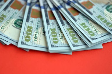 Kırmızı arka planda büyük miktarda yüz dolarlık banknot var. ABD 'de vergilendirme ve para yapma kavramı